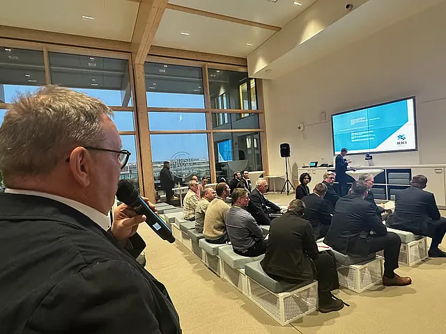 Man hält Mikrofon und stellt Frage in die Runde