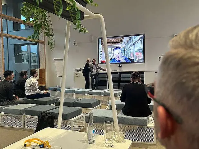 Mehre Personen sitzten in einem Konverenzraum und Höre dem Redner auf dem Monitor zu, zweite Veranstaltung von  KKI e.V. (Kompetenzzentrum Kritische Infrastrukturen e.V.) 2024